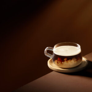 Beverage photography of a coffee set against a warm, dark chocolate background with dramatic lighting.